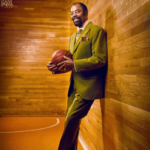 Walt Frazier dressed in a suit holding a basketball